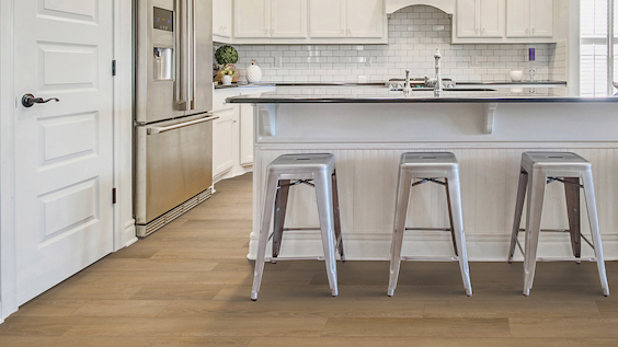 example of a kitchen remodel with warm wood look flooring, white cabinets, and tile backsplash